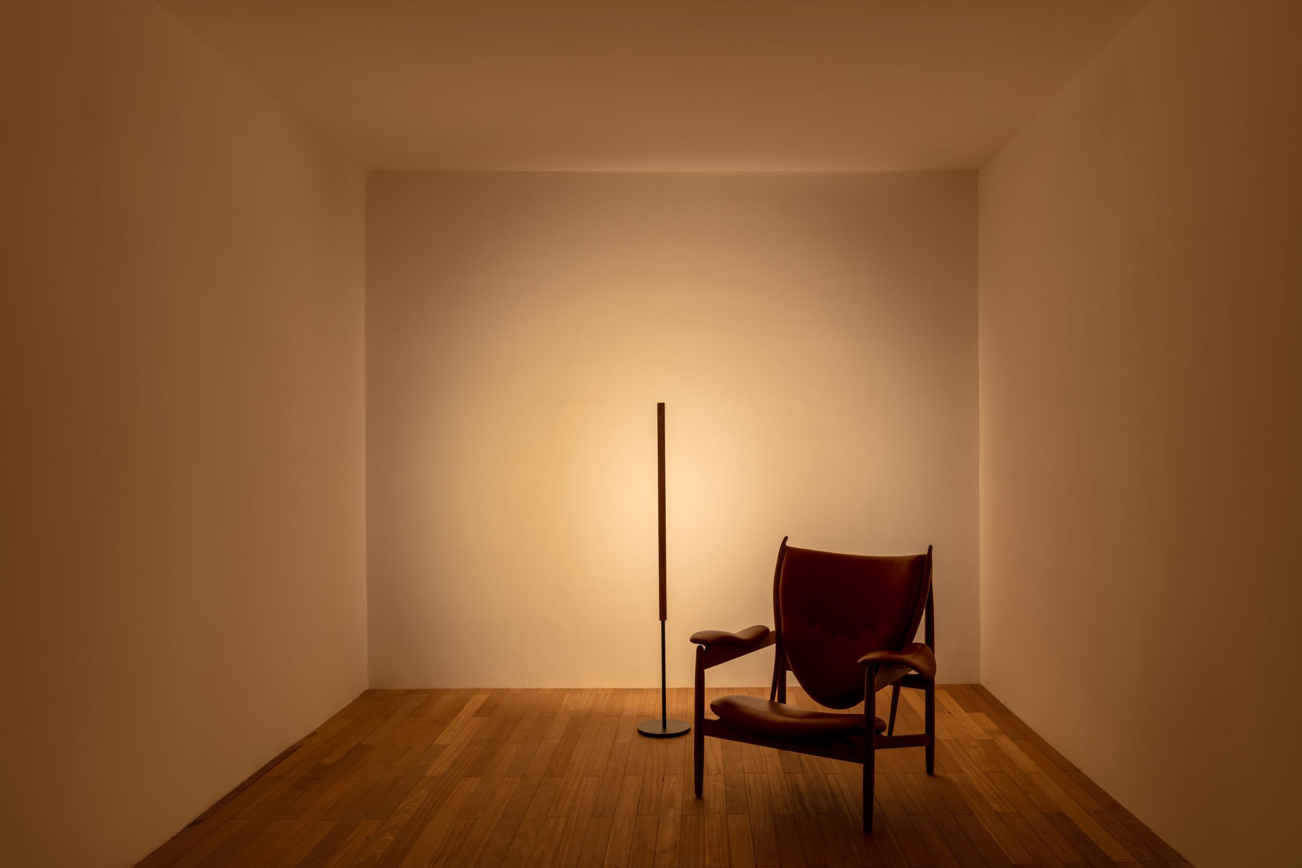 Lumatree Floor Wash photographed beside an armchair, directing light onto the wall